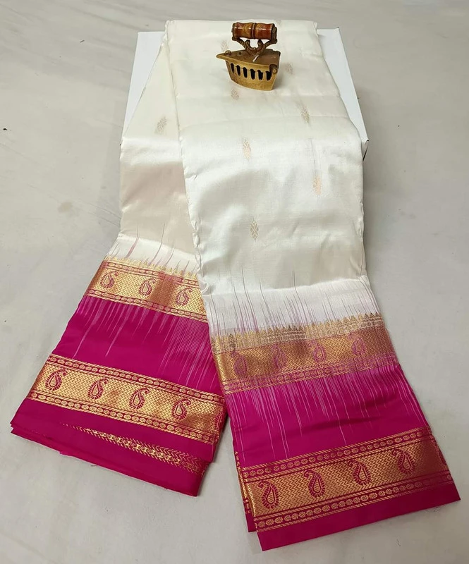 Off-white Kanchipuram silk saree with pink and gold Bentex border paisleys.